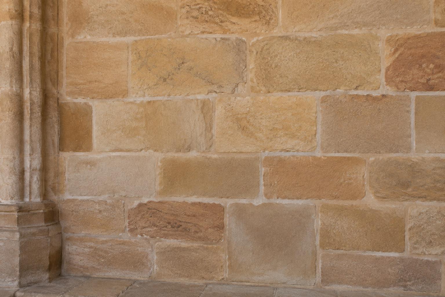 The same sandstone wall with soot removed and the natural stone colour visible.